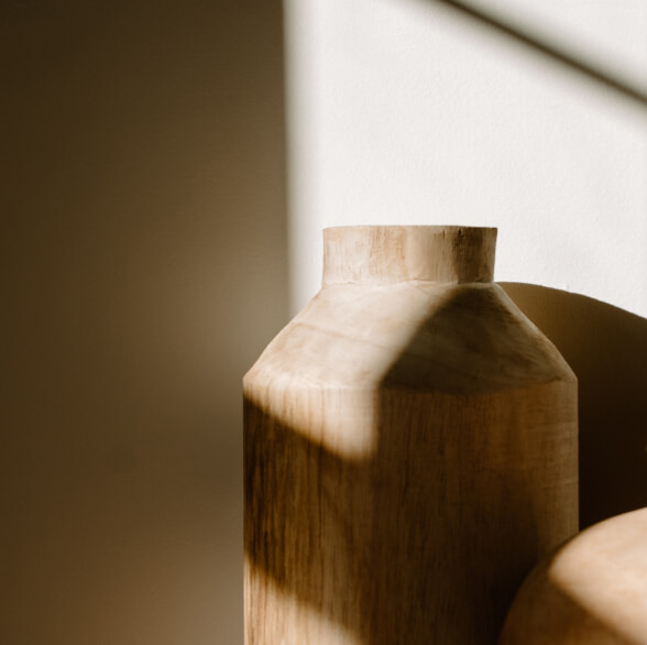 Close up of a stylish vase in a neutral colour, half in shadow and light.