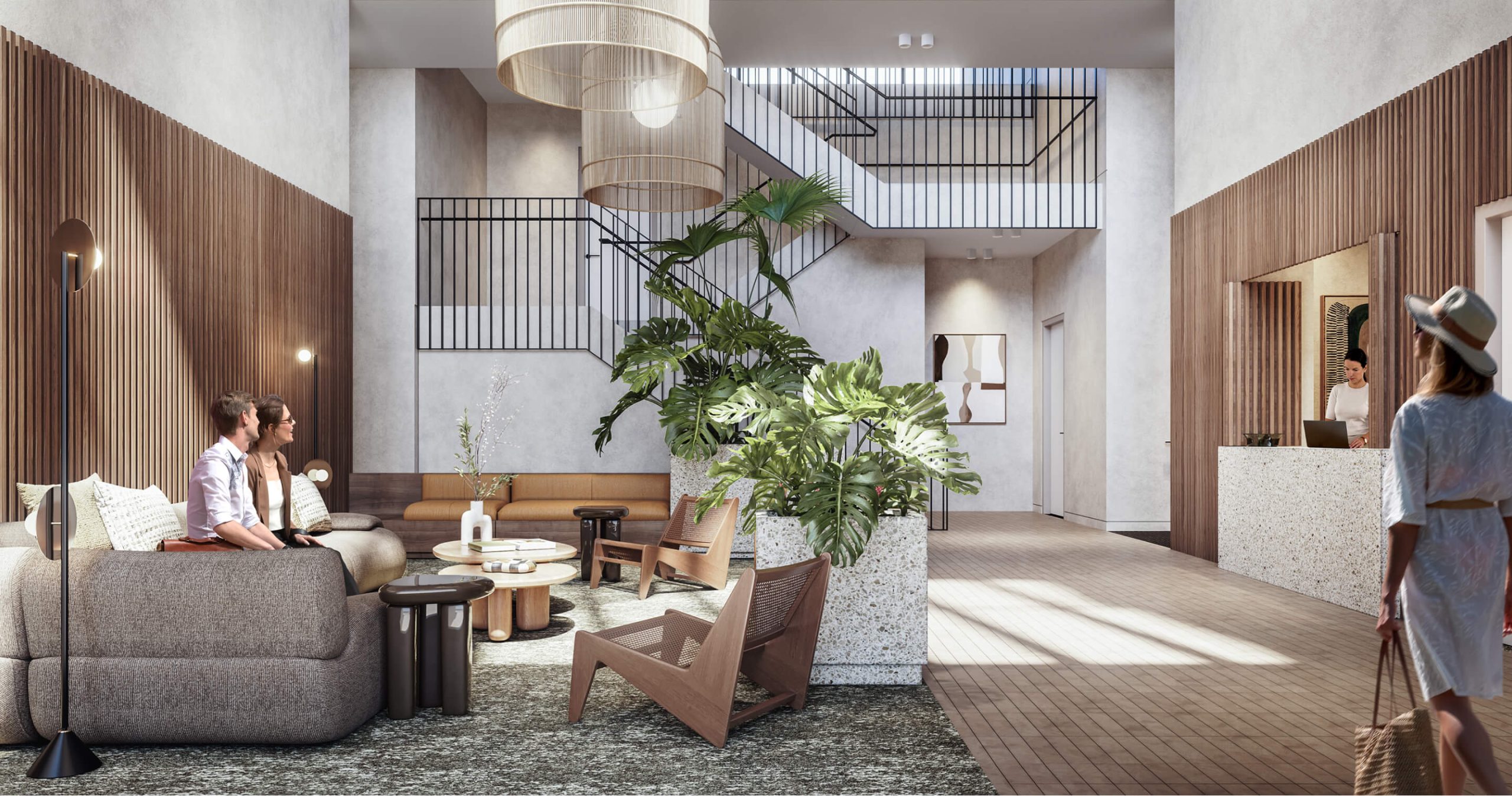 The main lobby at Wentworth Quarter, fit out warm timbers and textured white walls. A person waits behind the reception desk looking over at a seating area with lounges. Another heads to a staircase in the centre.